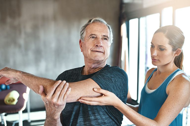 Get moving, get mobile. Shot of a senior man working out with the help of an instructor.