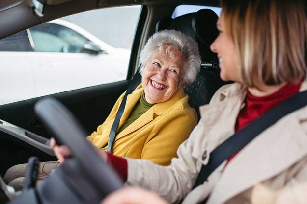 Granddaughter driving her elderly grandmother in the car, taking her to the doctor, shopping or to bank. Caregiver driving elderly lady to the church, pharmacy. Granddaughter driving her elderly grandmother in the car, taking her to the doctor, shopping or to bank. Caregiver driving elderly lady to the church, pharmacy.