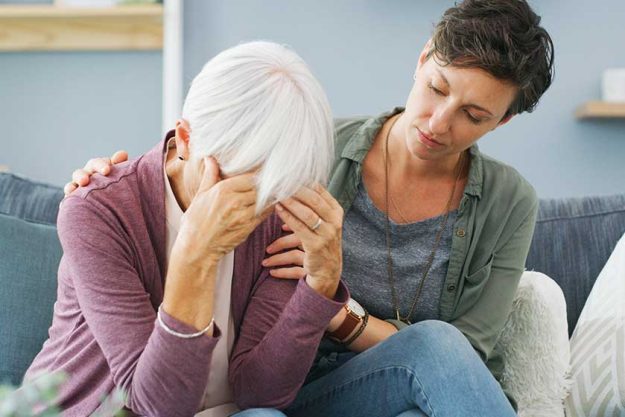 I have such a bad headache. an attractive young woman sitting and comforting her senior mother while she suffers from a headache