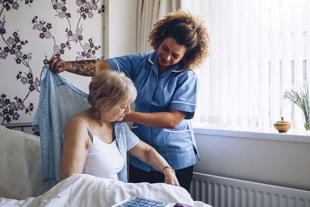 Home caregiver dressing senior