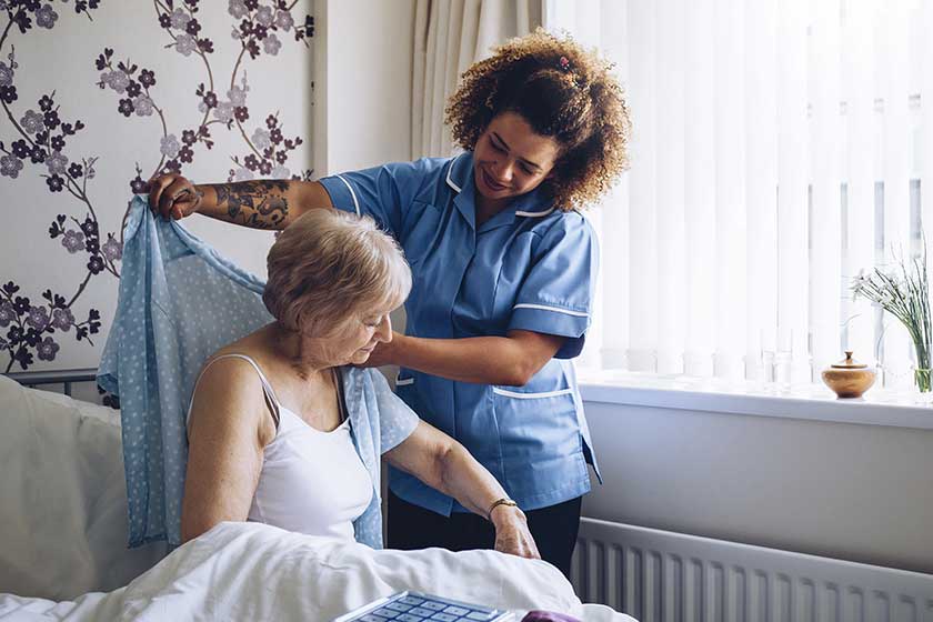 Home caregiver dressing senior