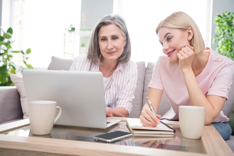 Photo of happy charming grey haired retired woman blonde lady sit sofa look laptop write note in house indoors