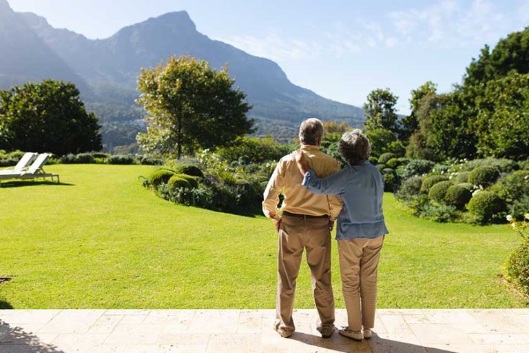 Senior caucasian couple standing and embracing in sunny garden. retreat, retirement and happy senior lifestyle concept