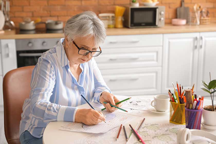 Senior woman coloring picture in kitchen