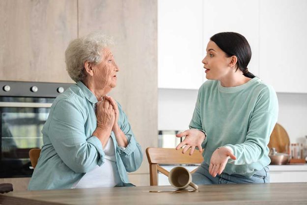 Senior woman and her daughter upset about spilled tea in kitchen Senior woman and her daughter upset about spilled tea in kitchen