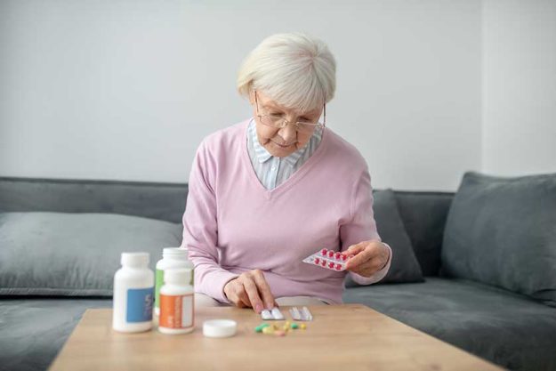 Senior woman with poor vision scrutinizing the medicines