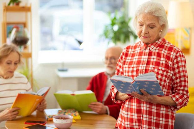 Serious grey haired woman standing with a book