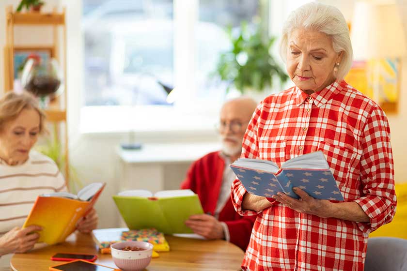 Serious grey haired woman standing with a book Serious grey haired woman standing with a book