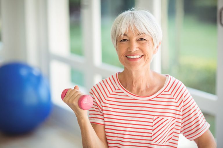 Portrait-of-senior-woman-exercising-with-dumbbell-at-home