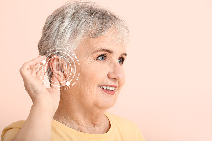 Senior-woman-with-hearing-aid-on-color-background