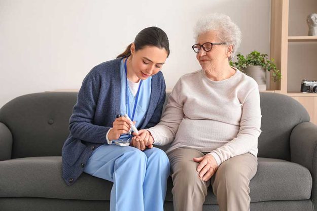 Young-caregiver-measuring-sugar-level-of-senior-woman Young-caregiver-measuring-sugar-level-of-senior-woman