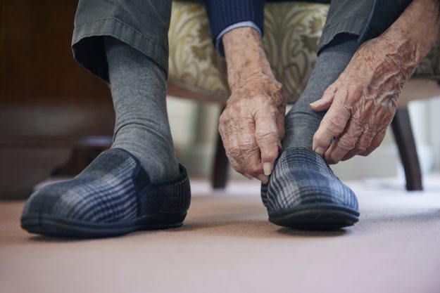 Close Up Of Senior Man Putting On Slippers To Keep Feet Warm In Close Up Of Senior Man Putting On Slippers To Keep Feet Warm In Cost Of Living Crisis — Photo
