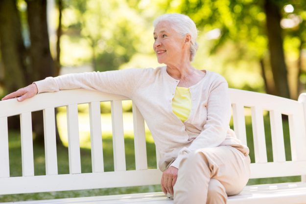 Happy senior woman sitting on bench at summer park — Photo Happy senior woman sitting on bench at summer park — Photo