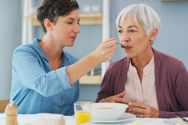 Isnt this delicious Mum. an attractive young woman helping and feeding her senior mother while they have breakfast together at home — Photo