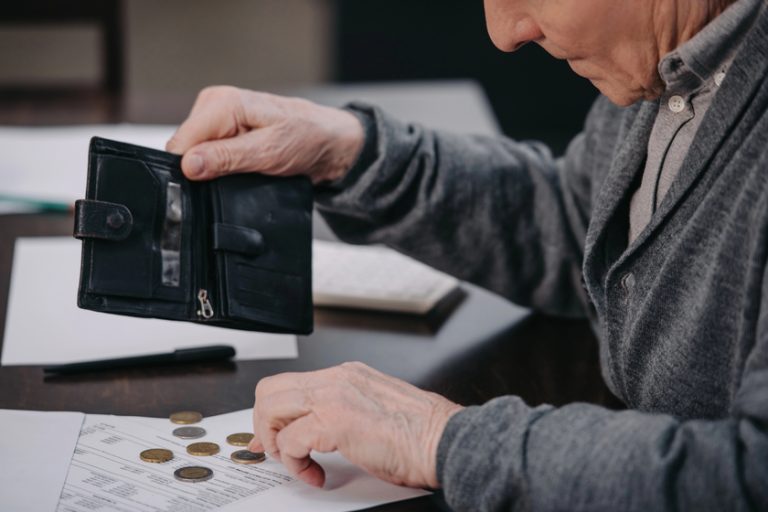 Male pensioner sitting at table with paperwork and counting money — Photo