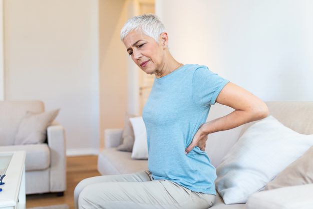 Upset mature middle aged woman feels back pain massaging aching muscles, sad senior older lady suffers from low-back lumbar pain sitting in incorrect sedentary posture, backache radiculitis concept Upset mature middle aged woman feels back pain massaging aching muscles, sad senior older lady suffers from low-back lumbar pain sitting in incorrect sedentary posture, backache radiculitis concept