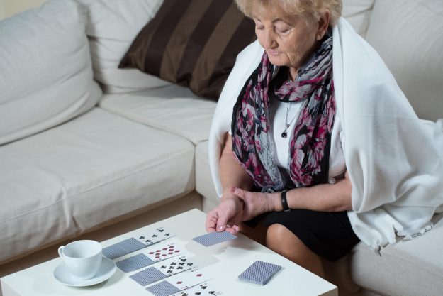 Senior,Woman,Sitting,On,The,Couch,And,Playing,Cards,Alone