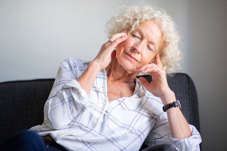 portrait-elderly-woman-sitting-sofa-headache-hands-head