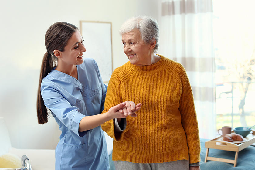 Care worker helping elderly woman to walk in geriatric