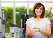 Smiling senior woman with fitness tracker over gym