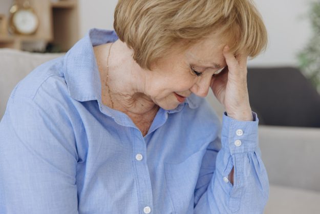 Sick older senior woman sit on sofa feel pain dizziness coping w
