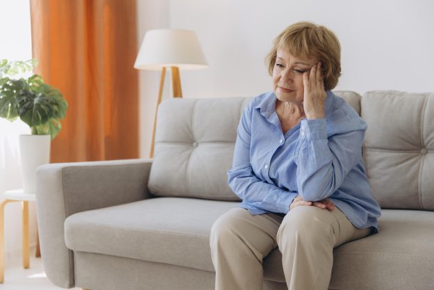 Sick older senior woman sit on sofa feel pain dizziness coping w