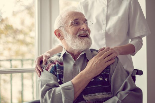Senior,Man,Sitting,On,The,Wheelchair,,Laughing,And,Holding,His