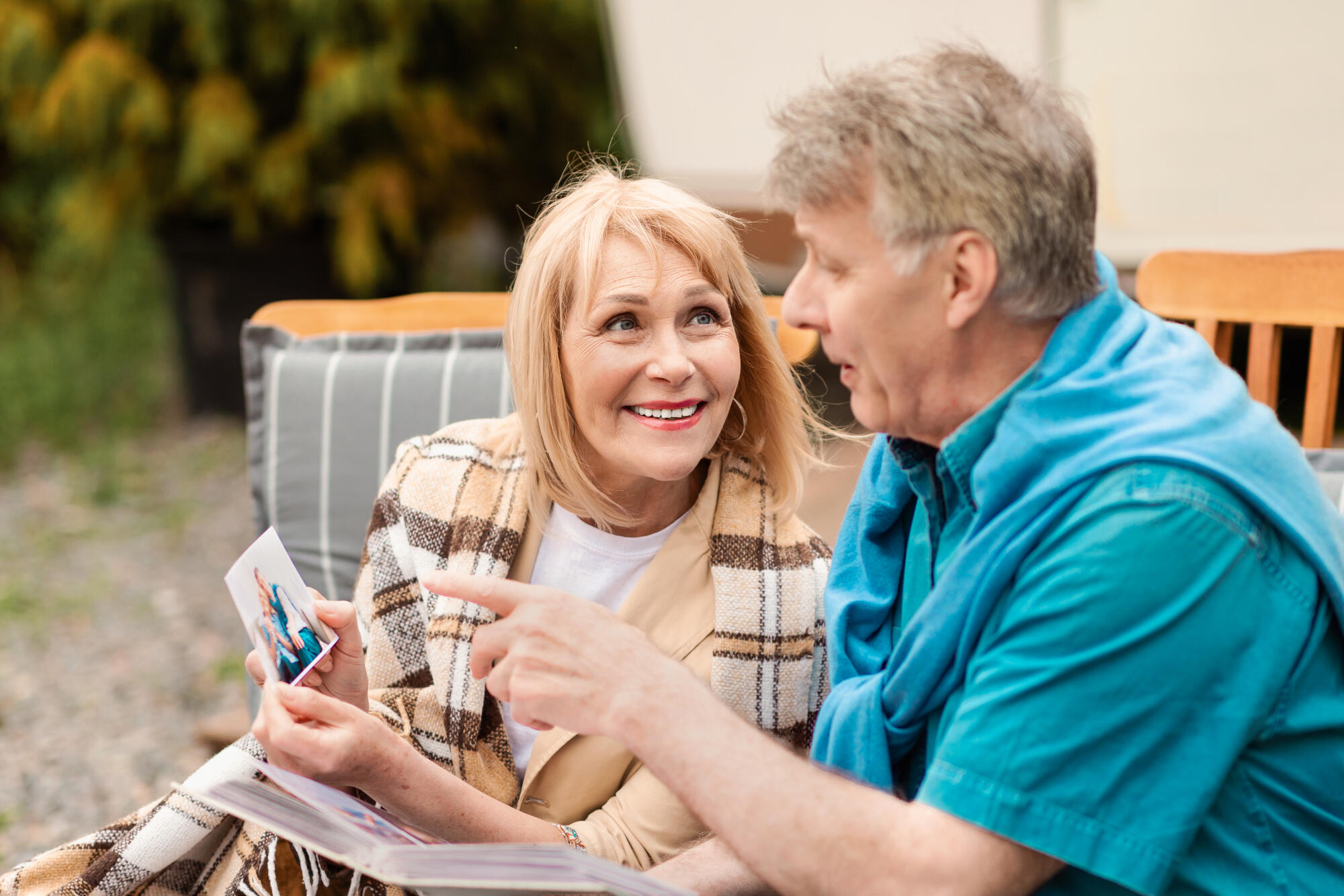 Happy memories. Elderly couple looking through family picture album near motorhome at campground