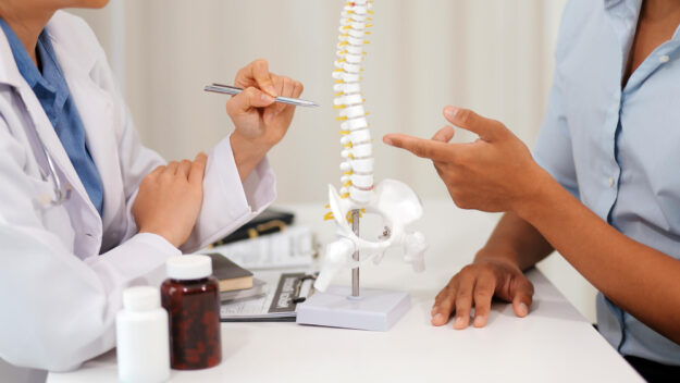 Orthopedists holding digital tablet and pointing at model. Conce