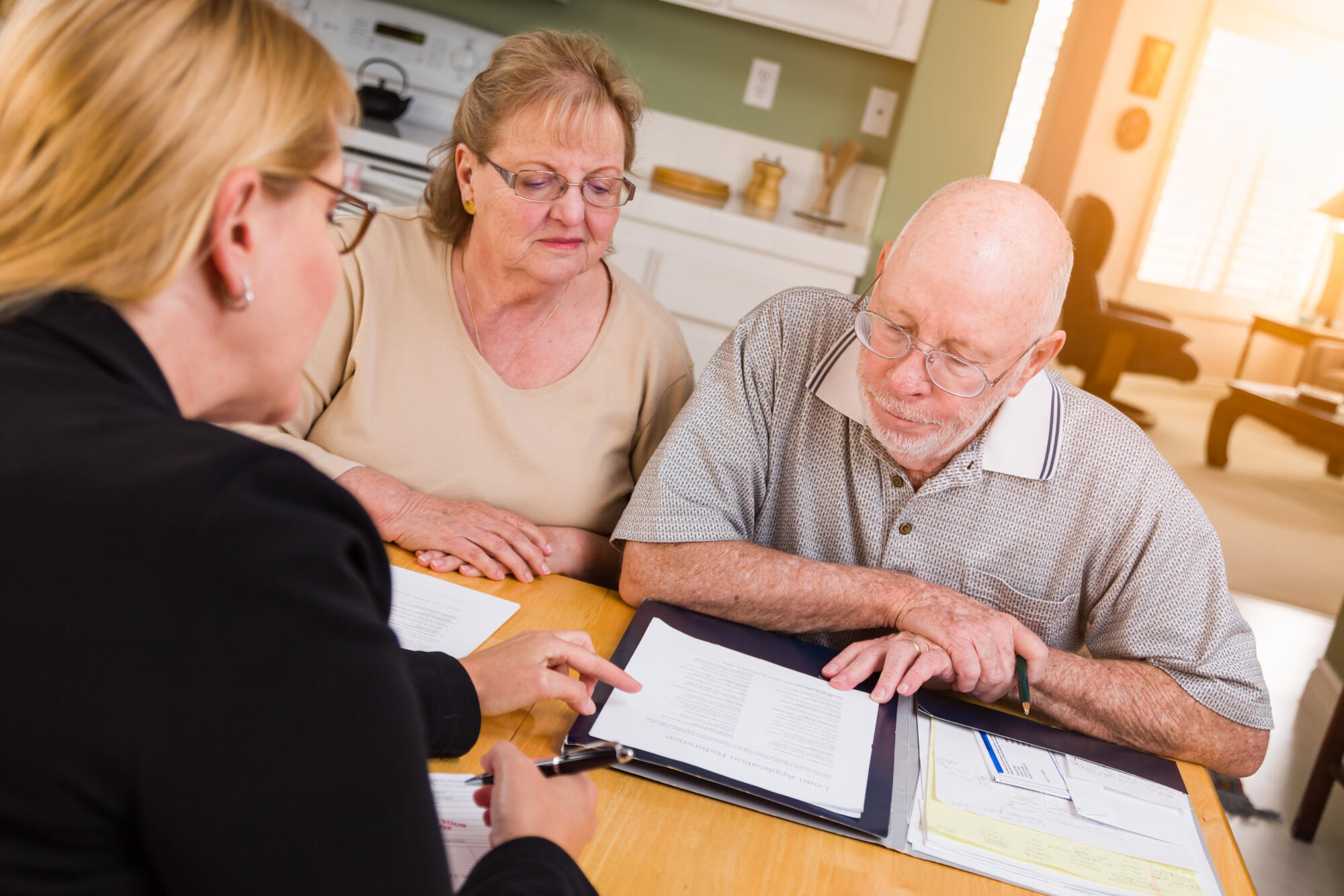 Senior Adult Couple Going Over Documents in Their Home with Agent At Signing.