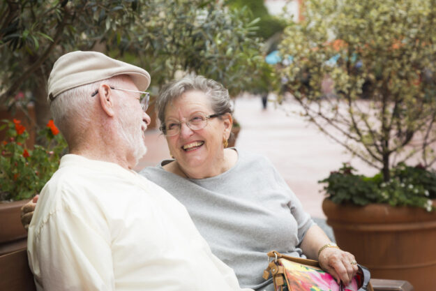 Happy Senior Couple Resting on a Bench in the Market Place.
