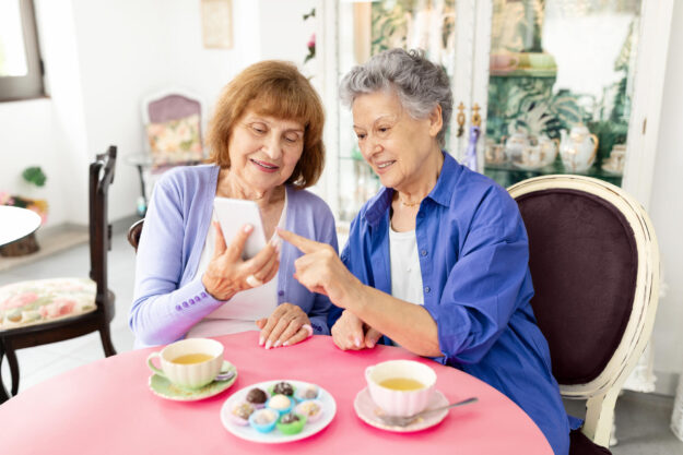 Elderly women enjoying a friendly conversation over tea and sweets at a cafe