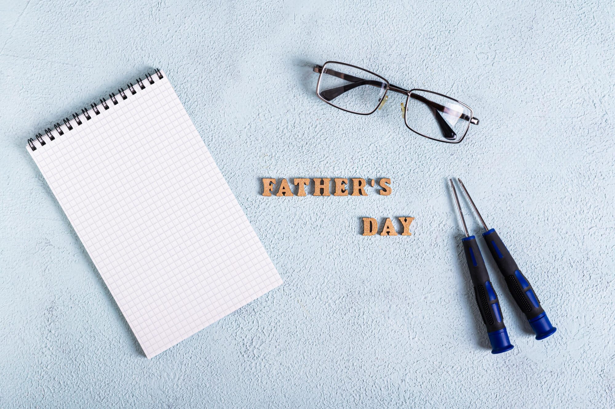 Father’s day open notepad, glasses and screwdrivers on blue text