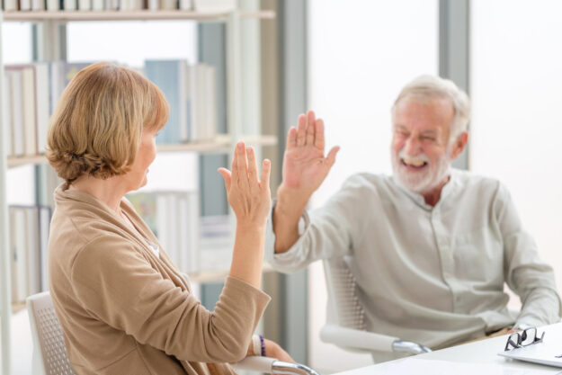 Happy senior couple in living room, Smiling older couple giving