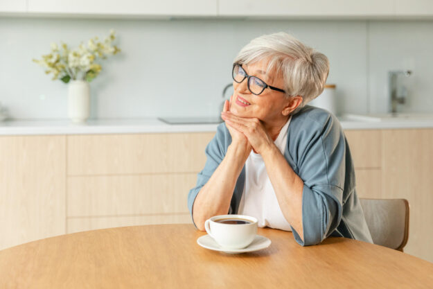 Good morning. Comfort relaxed senior old elderly woman grandmother drinking hot beverage tea coffee in kitchen at home. Mature woman resting enjoy calm morning at modern home alone. Pension concept.